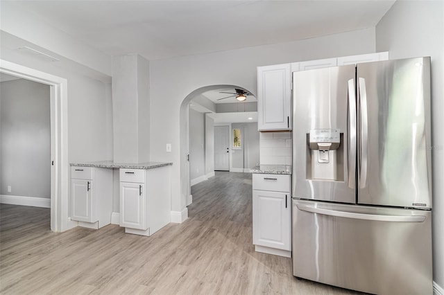 kitchen featuring stainless steel fridge, light hardwood / wood-style flooring, light stone counters, tasteful backsplash, and white cabinets