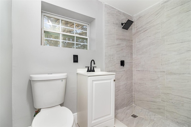 bathroom featuring vanity, toilet, and a tile shower