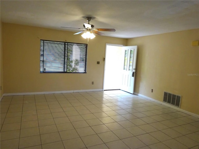 spare room featuring baseboards, light tile patterned flooring, visible vents, and a ceiling fan