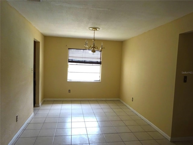spare room with light tile patterned floors, baseboards, and a chandelier