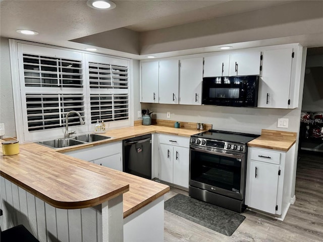 kitchen with sink, black appliances, light hardwood / wood-style flooring, kitchen peninsula, and white cabinets