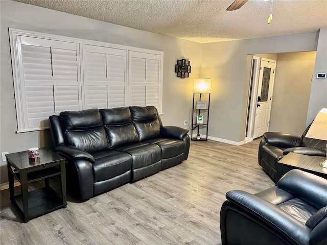 living room with ceiling fan, light hardwood / wood-style floors, and a textured ceiling