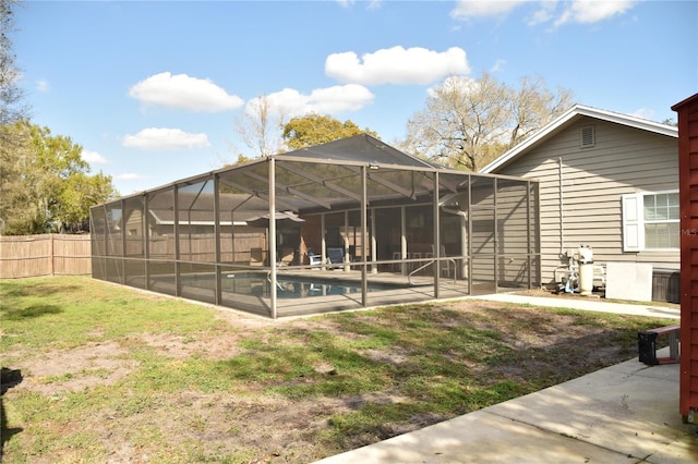 back of property featuring a fenced in pool, a patio area, a lawn, and glass enclosure