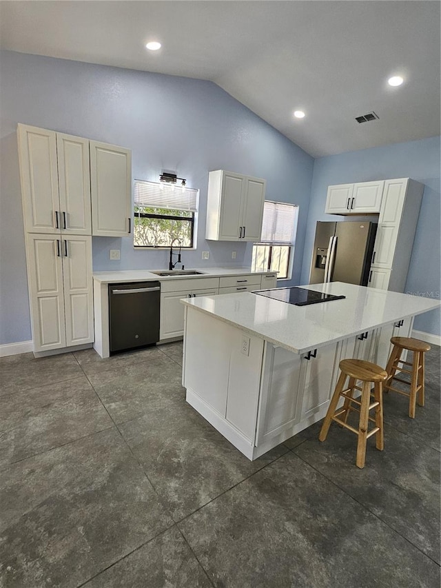 kitchen featuring sink, a breakfast bar, a center island, black appliances, and white cabinets
