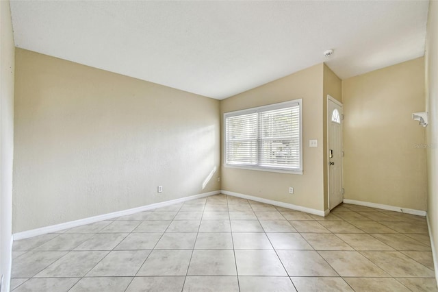 empty room with lofted ceiling and light tile patterned floors