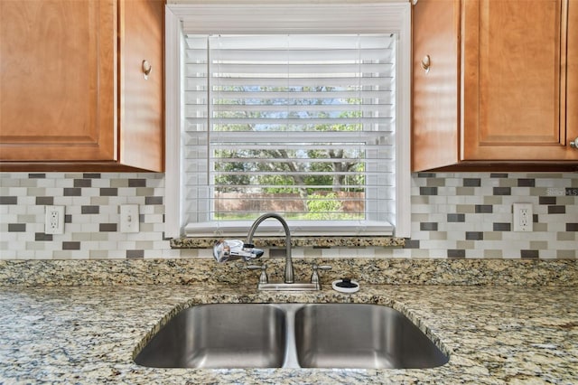 kitchen featuring light stone counters, sink, and backsplash