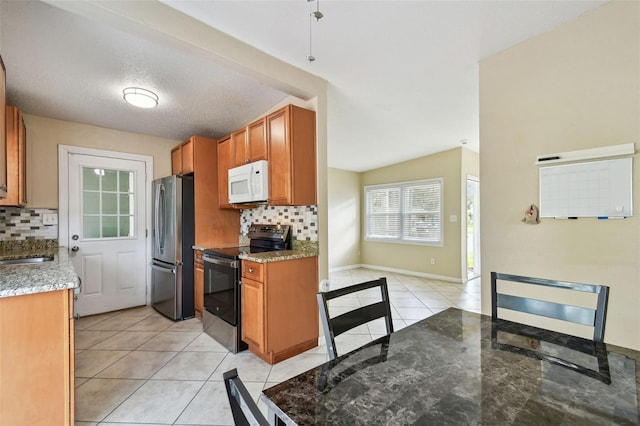 kitchen featuring light tile patterned flooring, decorative backsplash, appliances with stainless steel finishes, and light stone counters