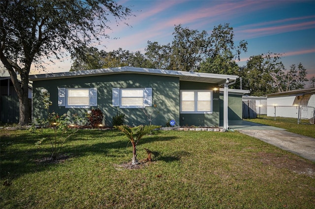 view of front of property featuring a lawn, driveway, and fence