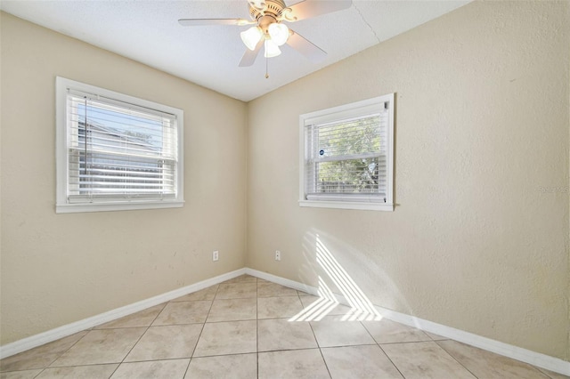 unfurnished room with light tile patterned floors, ceiling fan, baseboards, and a textured wall