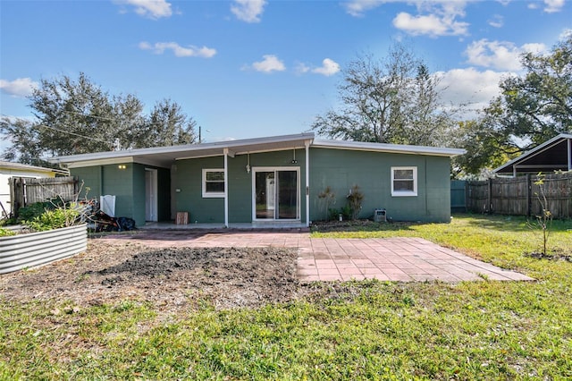 back of property featuring a lawn, concrete block siding, a patio, and fence