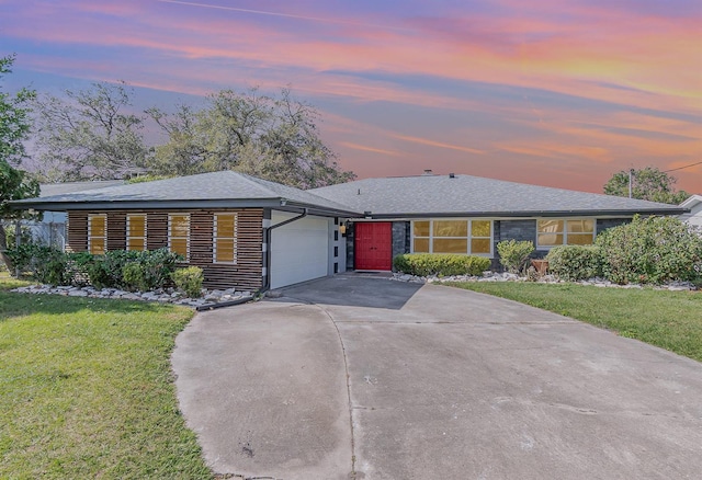 single story home featuring a garage and a yard