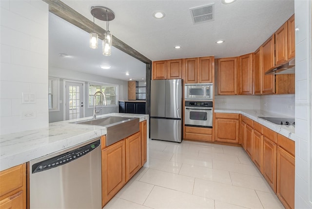 kitchen with sink, appliances with stainless steel finishes, pendant lighting, light stone countertops, and backsplash