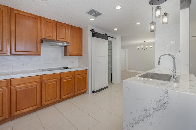 kitchen featuring sink, tasteful backsplash, decorative light fixtures, black electric stovetop, and a barn door