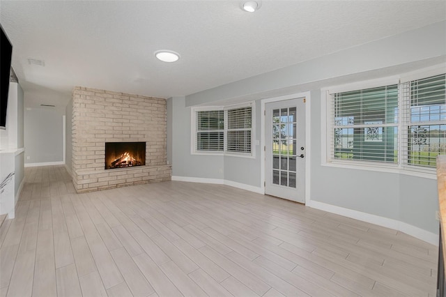 unfurnished living room with a fireplace, light hardwood / wood-style floors, and a textured ceiling