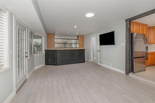 interior space featuring sink, light hardwood / wood-style flooring, and a textured ceiling