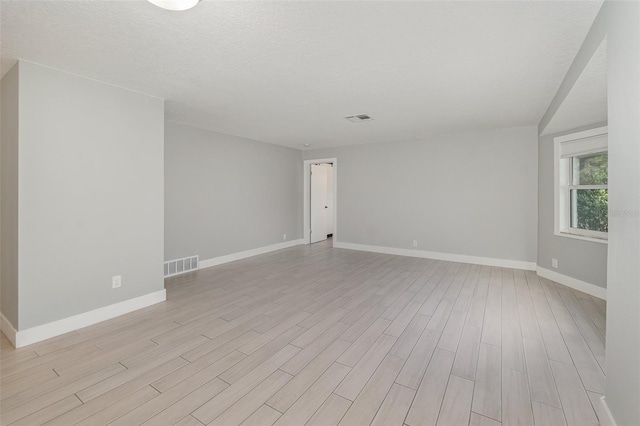 spare room featuring a textured ceiling and light hardwood / wood-style floors