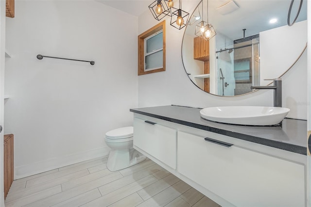 bathroom with vanity, a shower with door, and toilet