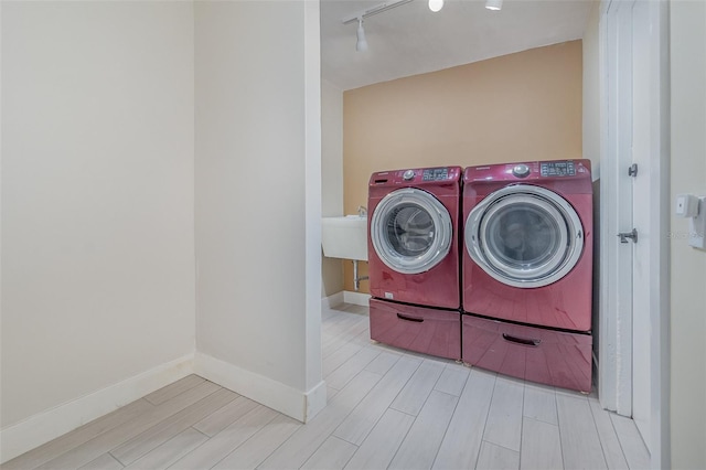 clothes washing area featuring sink, washer and clothes dryer, and track lighting