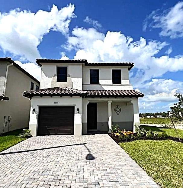 mediterranean / spanish-style house featuring a garage and a front lawn