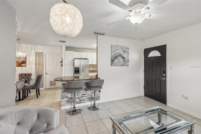 tiled foyer with ceiling fan with notable chandelier