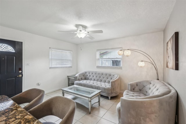 living room with ceiling fan, a textured ceiling, and light tile patterned floors