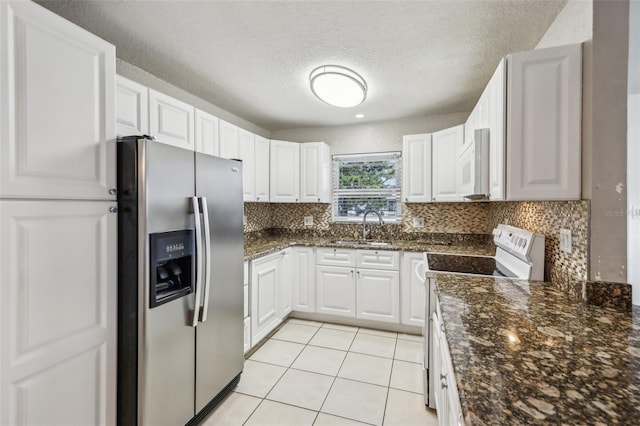 kitchen featuring sink, dark stone countertops, white cabinets, light tile patterned floors, and white appliances