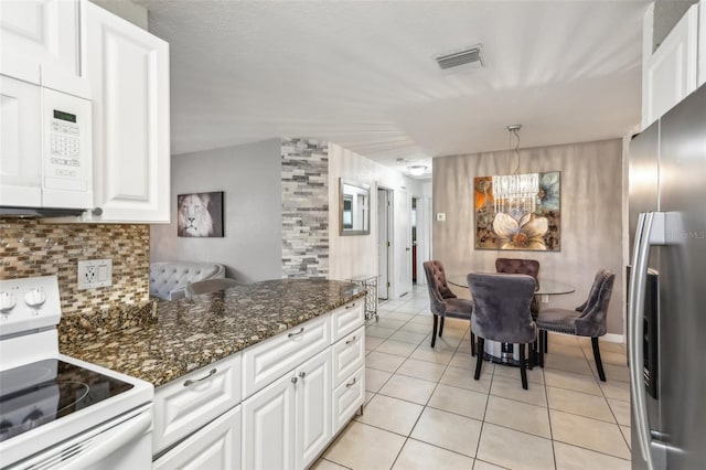 kitchen featuring white appliances, hanging light fixtures, white cabinets, decorative backsplash, and dark stone counters