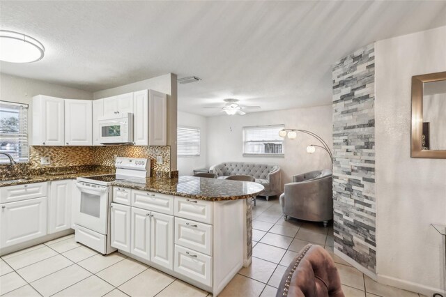 kitchen featuring sink, dark stone countertops, kitchen peninsula, white appliances, and white cabinets