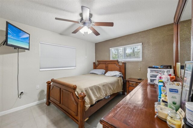 bedroom featuring ceiling fan, light tile patterned floors, and a textured ceiling