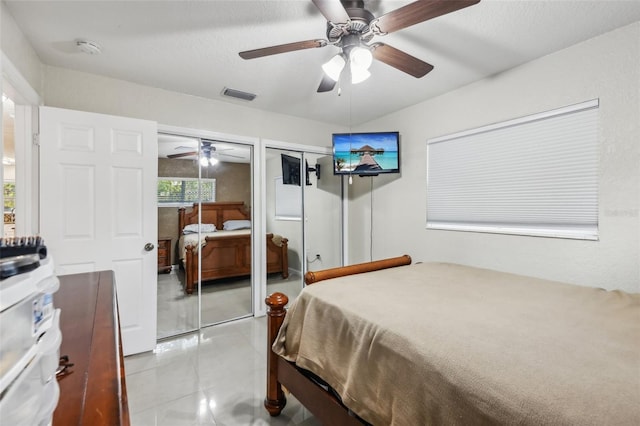 bedroom featuring ceiling fan, light tile patterned floors, and multiple closets