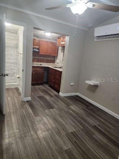 kitchen featuring sink, dark hardwood / wood-style flooring, ornamental molding, exhaust hood, and a wall unit AC