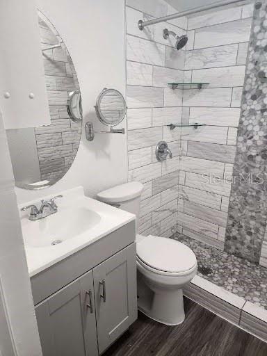 bathroom featuring vanity, toilet, hardwood / wood-style floors, and a tile shower