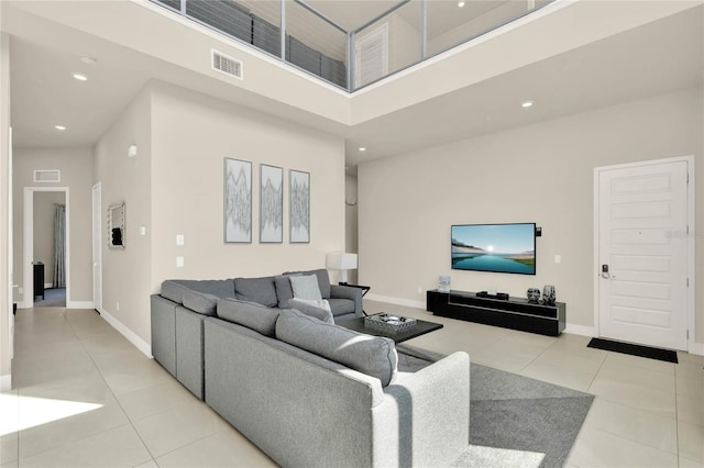 living room with a towering ceiling and light tile patterned floors