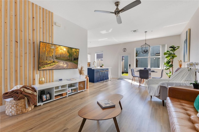 living room featuring ceiling fan, sink, and light wood-type flooring