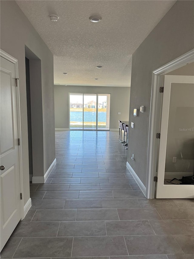 hall with a water view and a textured ceiling