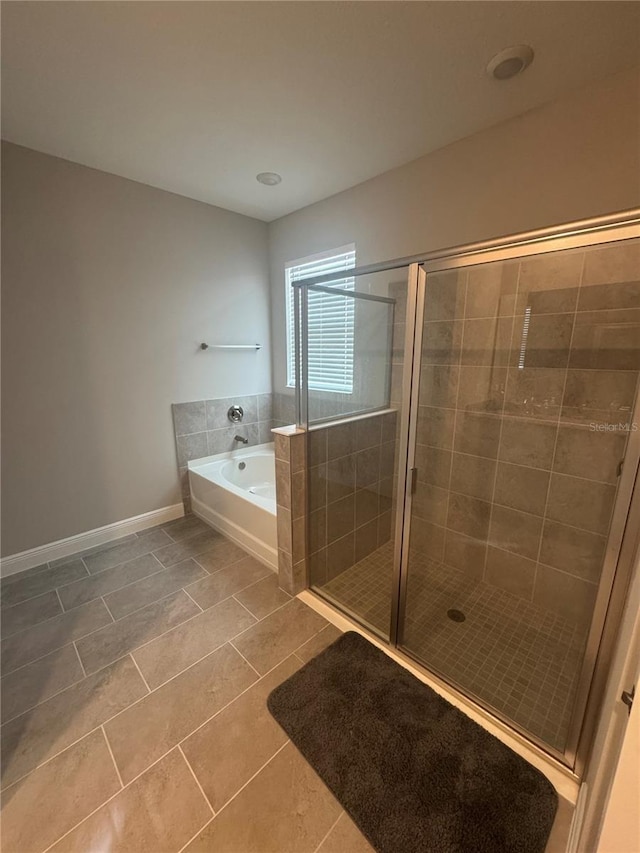 full bathroom featuring a garden tub, baseboards, and a stall shower