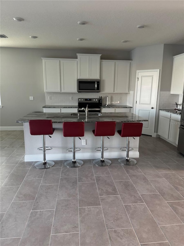 kitchen featuring stainless steel appliances, a kitchen bar, and white cabinetry