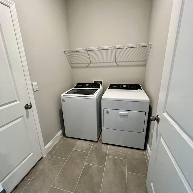 clothes washing area with laundry area, washing machine and dryer, and baseboards