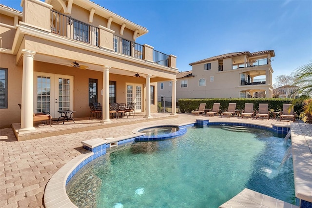 view of pool with a patio, an in ground hot tub, pool water feature, ceiling fan, and french doors