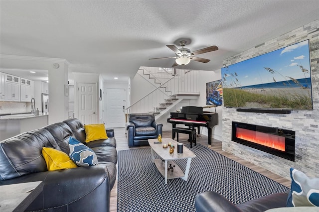 living room featuring hardwood / wood-style flooring, ceiling fan, a fireplace, and a textured ceiling