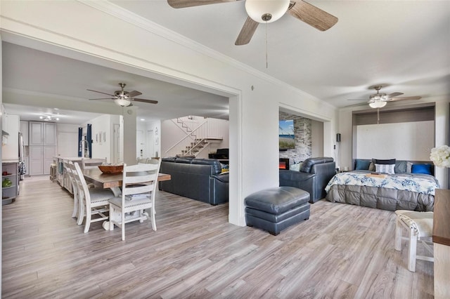 bedroom featuring ceiling fan, ornamental molding, a fireplace, and light hardwood / wood-style floors