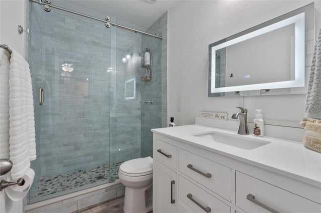 bathroom with vanity, toilet, a shower with shower door, and hardwood / wood-style floors