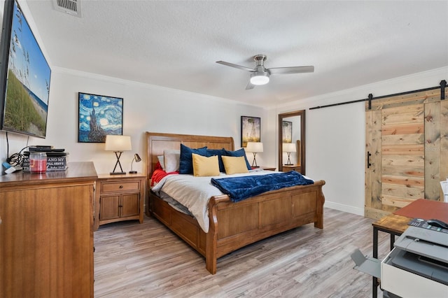 bedroom featuring crown molding, a barn door, a textured ceiling, and light hardwood / wood-style flooring