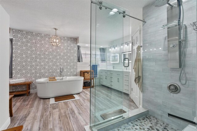 bathroom featuring vanity, independent shower and bath, wood-type flooring, and a textured ceiling