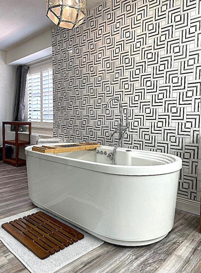 bathroom with hardwood / wood-style floors, a textured ceiling, and a bathtub