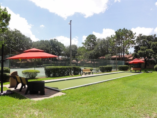 view of property's community featuring a yard and tennis court