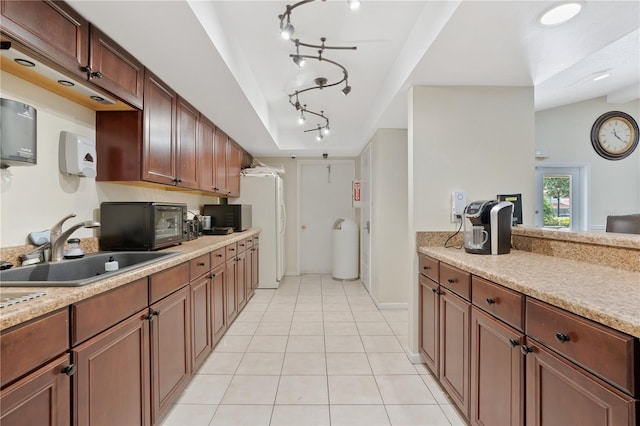 kitchen with light tile patterned flooring, lofted ceiling, sink, light stone counters, and white refrigerator