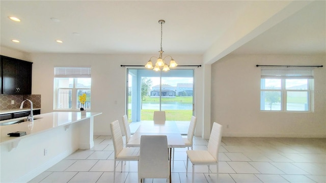 tiled dining room featuring sink, a wealth of natural light, and an inviting chandelier