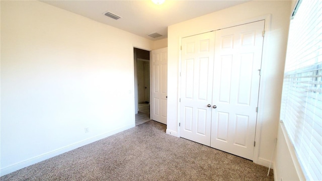 unfurnished bedroom with light colored carpet and a closet