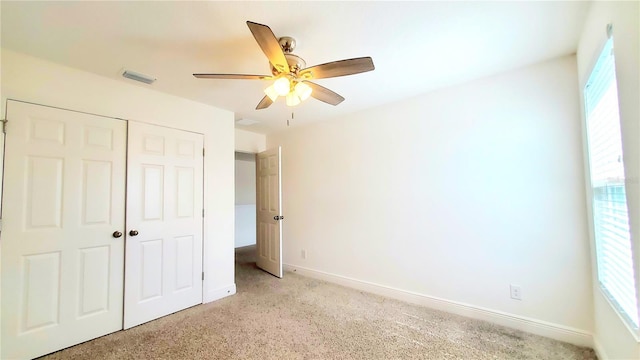 unfurnished bedroom featuring ceiling fan, light colored carpet, and a closet